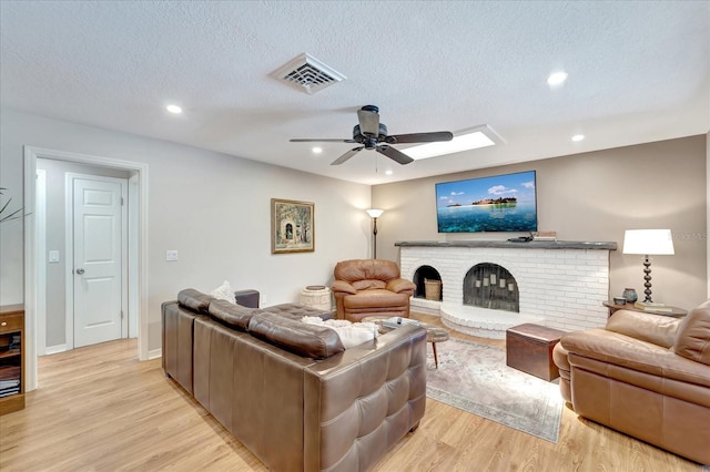 1515 Pecan St, Nokomis, FL 34275 - living area featuring light wood-style flooring, ceiling fan, a fireplace, recessed lighting, and a textured ceiling