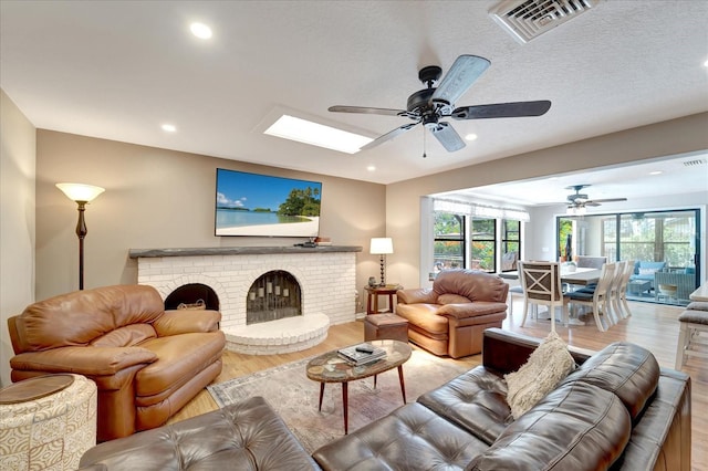 1515 Pecan St, Nokomis, FL 34275 - living area featuring a ceiling fan, light wood-style flooring, a brick fireplace, recessed lighting, and a skylight