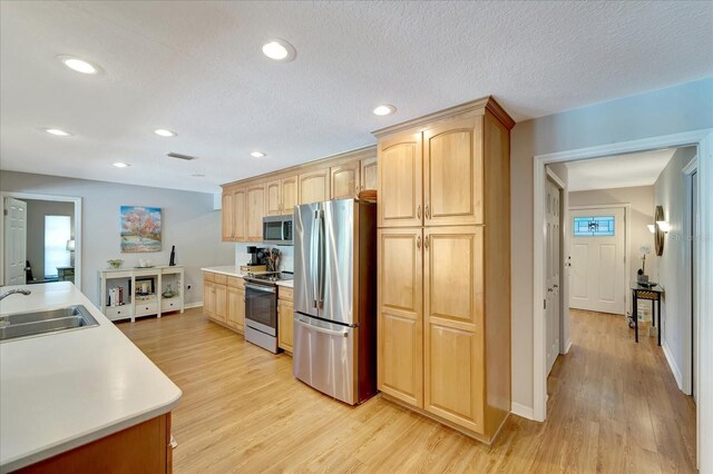 1515 Pecan St, Nokomis, FL 34275 - kitchen featuring stainless steel appliances, a sink, light wood-style flooring, light brown cabinets, and baseboards