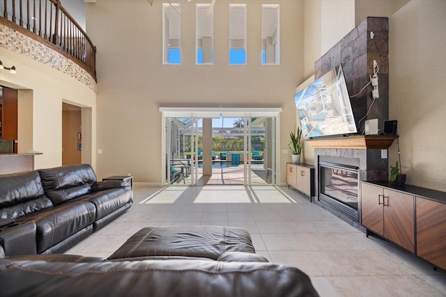2322 Bayshore Rd, Nokomis, FL 34275 - living area with a tiled fireplace, a towering ceiling, light tile patterned floors, and baseboards