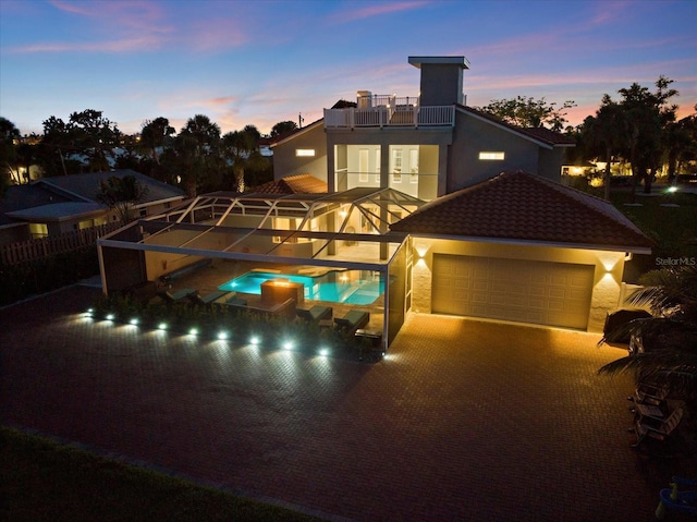 2322 Bayshore Rd, Nokomis, FL 34275 - back of property at dusk featuring a balcony, a pool with connected hot tub, stucco siding, a tiled roof, and a garage