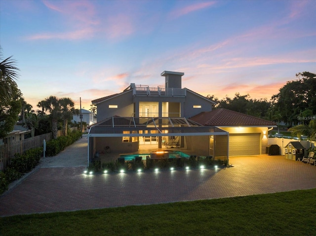 2322 Bayshore Rd, Nokomis, FL 34275 - back of house at dusk with a balcony, a garage, stucco siding, decorative driveway, and a patio area