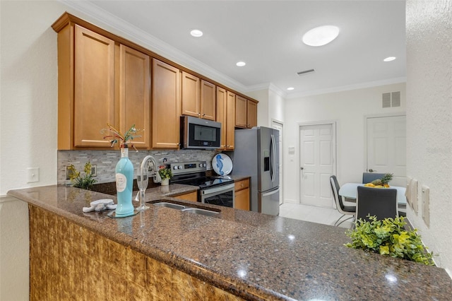 2104 Batello Dr, Venice, FL 34292 - kitchen featuring stainless steel appliances, dark stone counters, brown cabinetry, decorative backsplash, and crown molding