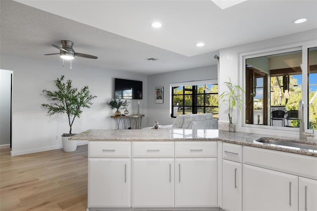 5140 Administration St, Port Charlotte, FL 33948 - kitchen featuring a wainscoted wall, a sink, a peninsula, light wood-style flooring, and light stone countertops