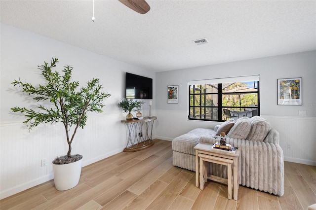 5140 Administration St, Port Charlotte, FL 33948 - living area featuring a wainscoted wall, light wood finished floors, a textured ceiling, and ceiling fan