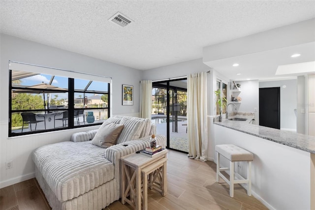 5140 Administration St, Port Charlotte, FL 33948 - bedroom featuring a sink, access to exterior, light wood-style floors, baseboards, and a textured ceiling