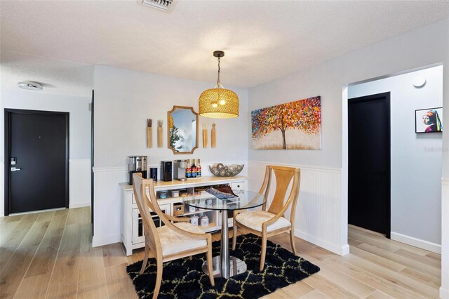 5140 Administration St, Port Charlotte, FL 33948 - dining space with a wainscoted wall, light wood-style flooring, and a textured ceiling