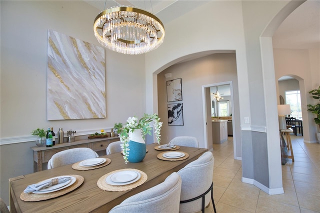 8209 Snowy Egret Pl, Bradenton, FL 34202 - dining room with light tile patterned flooring, a chandelier, arched walkways, and baseboards