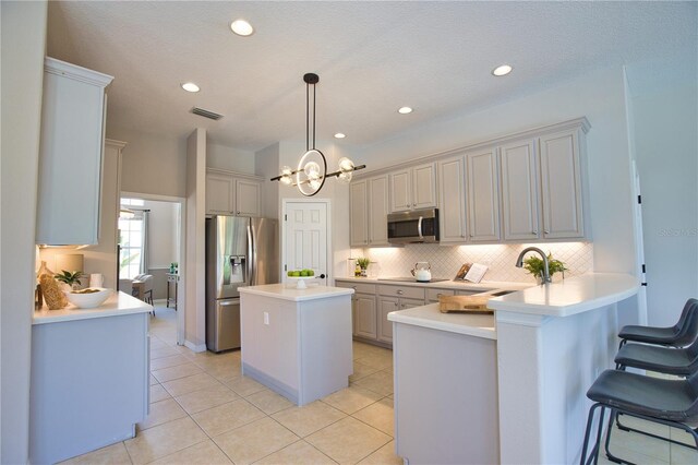 8209 Snowy Egret Pl, Bradenton, FL 34202 - kitchen featuring appliances with stainless steel finishes, tasteful backsplash, a center island, a peninsula, and light countertops