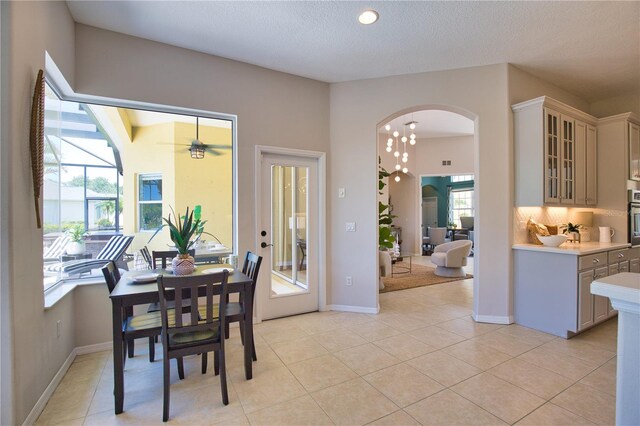 8209 Snowy Egret Pl, Bradenton, FL 34202 - dining area with arched walkways, light tile patterned floors, baseboards, a ceiling fan, and a textured ceiling