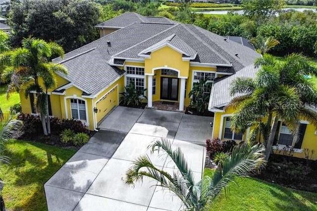 8209 Snowy Egret Pl, Bradenton, FL 34202 - view of front of property featuring an attached garage, concrete driveway, stucco siding, a front yard, and roof with shingles