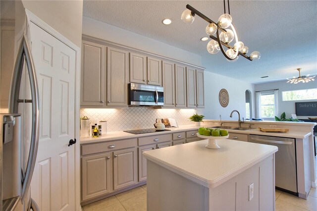 8209 Snowy Egret Pl, Bradenton, FL 34202 - kitchen featuring stainless steel appliances, a sink, a peninsula, light tile patterned floors, and a textured ceiling