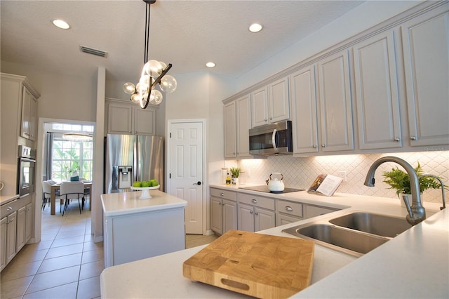 8209 Snowy Egret Pl, Bradenton, FL 34202 - kitchen featuring appliances with stainless steel finishes, a kitchen island, a sink, tasteful backsplash, and decorative light fixtures