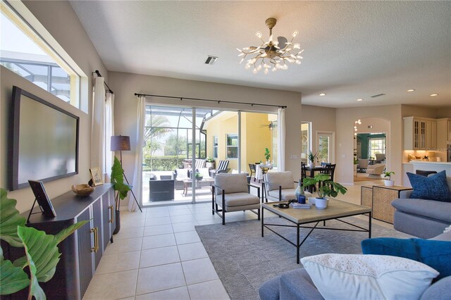 8209 Snowy Egret Pl, Bradenton, FL 34202 - living area with a chandelier, light tile patterned flooring, recessed lighting, a textured ceiling, and arched walkways