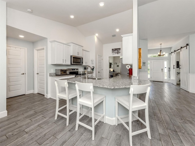 460 Bard Rd, Venice, FL 34293 - kitchen with appliances with stainless steel finishes, a barn door, wood finished floors, a sink, and a breakfast bar
