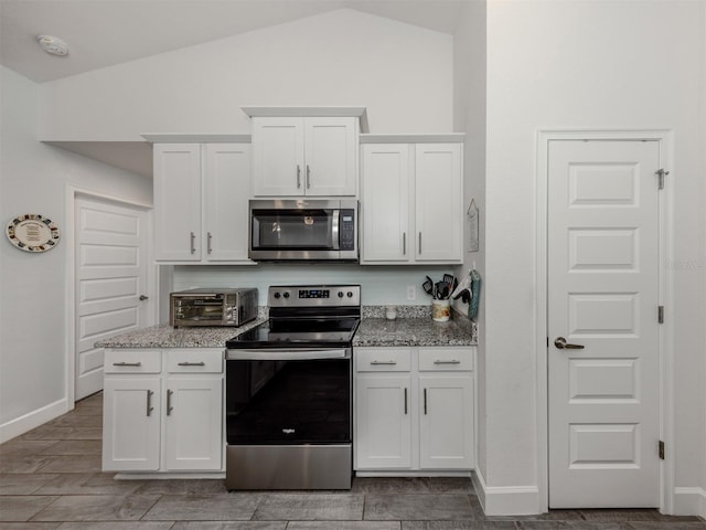 460 Bard Rd, Venice, FL 34293 - kitchen with appliances with stainless steel finishes, lofted ceiling, light stone countertops, white cabinets, and baseboards