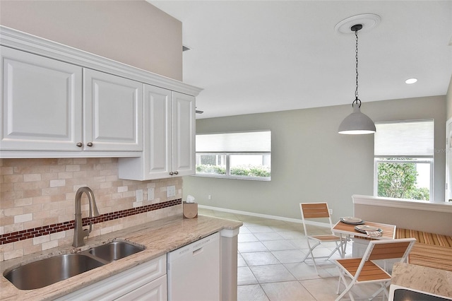 1104 Auburn Cove Cir, Venice, FL 34292 - kitchen with dishwasher, a sink, backsplash, baseboards, and white cabinetry