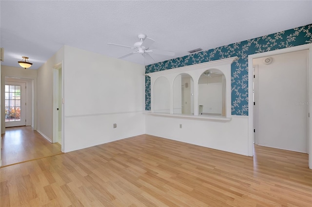 915 S Doral Ln, Venice, FL 34293 - spare room featuring ceiling fan, wood finished floors, wallpapered walls, and a textured ceiling