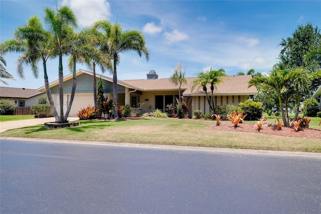915 S Doral Ln, Venice, FL 34293 - view of front of home featuring an attached garage, a front lawn, driveway, and a chimney