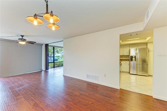 618 Bird Bay Dr S Unit 110, Venice, FL 34285 - spare room featuring light wood-style floors, floor to ceiling windows, a ceiling fan, baseboards, and a chandelier