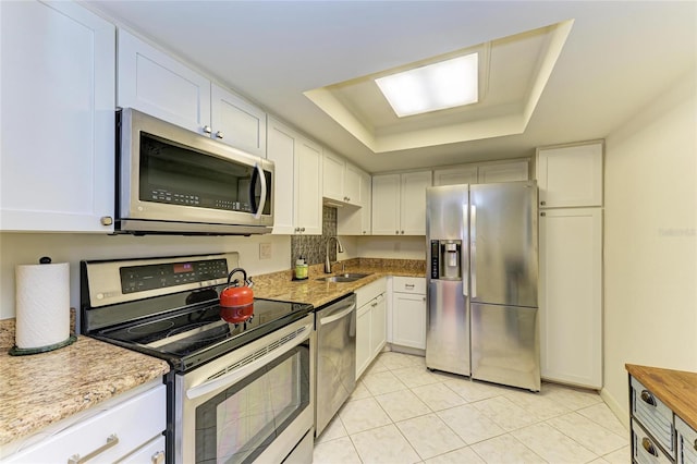 618 Bird Bay Dr S Unit 110, Venice, FL 34285 - kitchen featuring appliances with stainless steel finishes, a sink, a tray ceiling, light tile patterned floors, and white cabinets