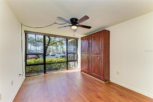 618 Bird Bay Dr S Unit 110, Venice, FL 34285 - spare room with wood finished floors, a ceiling fan, baseboards, and floor to ceiling windows