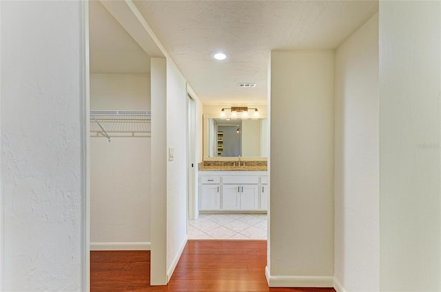618 Bird Bay Dr S Unit 110, Venice, FL 34285 - hallway featuring wood finished floors, baseboards, and a sink