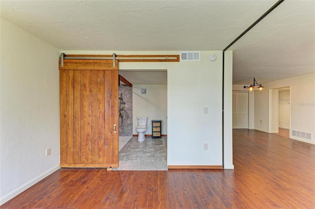 618 Bird Bay Dr S Unit 110, Venice, FL 34285 - spare room with wood finished floors, baseboards, a barn door, a textured ceiling, and a smoke detector