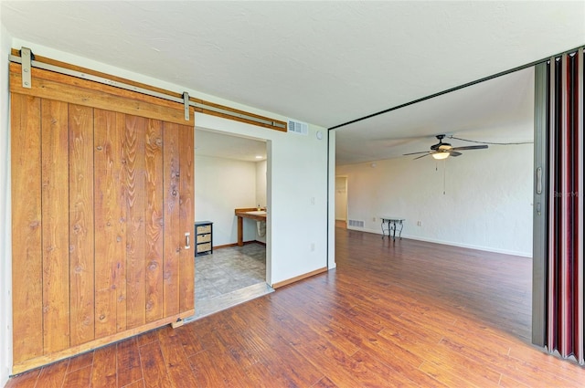 618 Bird Bay Dr S Unit 110, Venice, FL 34285 - unfurnished room with a barn door, wood finished floors, a ceiling fan, and baseboards