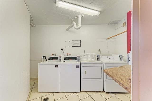 618 Bird Bay Dr S Unit 110, Venice, FL 34285 - community laundry room with washer and clothes dryer, light tile patterned floors, and a textured ceiling