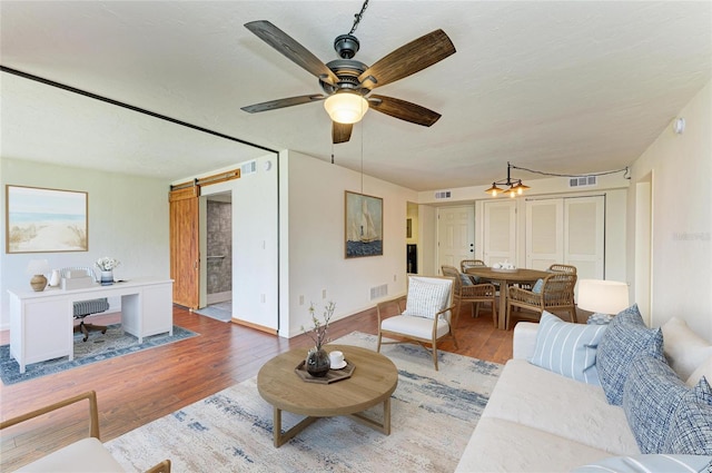 618 Bird Bay Dr S Unit 110, Venice, FL 34285 - living room featuring wood finished floors, ceiling fan, and a barn door
