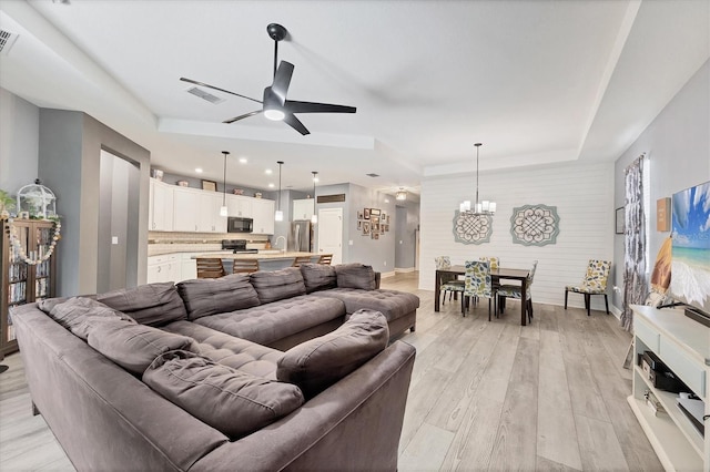2034 Mesic Hammock Way, Venice, FL 34292 - living room featuring ceiling fan, a chandelier, a tray ceiling, light wood-style flooring, and baseboards