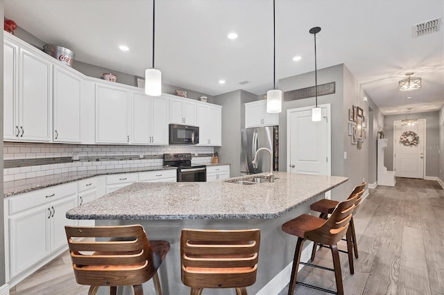 2034 Mesic Hammock Way, Venice, FL 34292 - kitchen with stainless steel appliances, a sink, tasteful backsplash, a kitchen island with sink, and baseboards