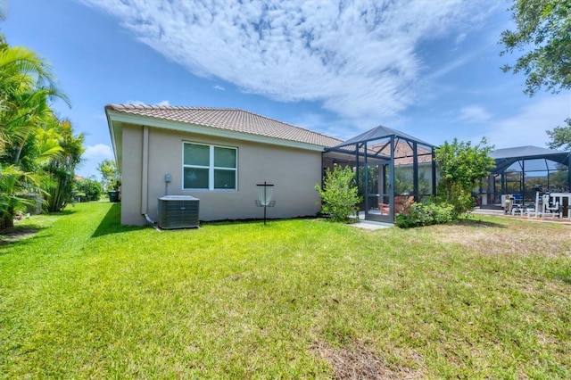 2034 Mesic Hammock Way, Venice, FL 34292 - rear view of property featuring stucco siding, central AC unit, a tiled roof, a lawn, and glass enclosure