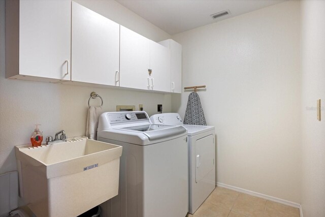 9277 Saint Catherine Ave, Englewood, FL 34224 - washroom with cabinet space, washer and dryer, baseboards, and light tile patterned floors