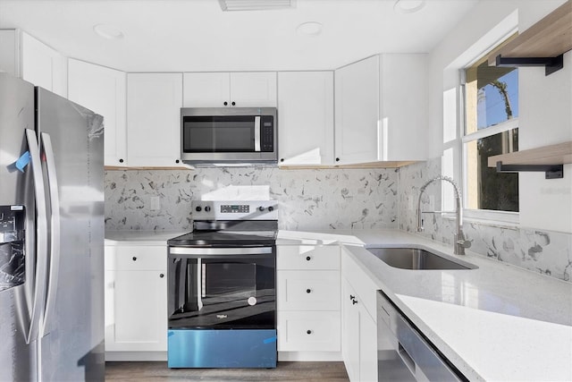1032 Elaine St, Venice, FL 34285 - kitchen with appliances with stainless steel finishes, a sink, open shelves, wood finished floors, and white cabinetry