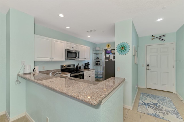 8409 Placida Rd Unit 206, Placida, FL 33946 - kitchen featuring stainless steel appliances, light stone countertops, a peninsula, light tile patterned floors, and white cabinetry