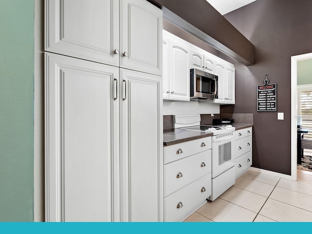 114 Southampton Pl N Unit 237, Venice, FL 34293 - kitchen with stainless steel microwave, electric range, dark countertops, white cabinets, and light tile patterned flooring