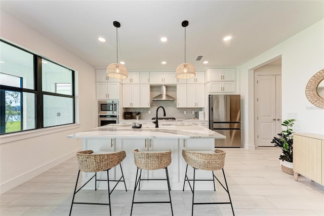 12816 Morning Mist Pl, Venice, FL 34293 - kitchen featuring appliances with stainless steel finishes, wall chimney exhaust hood, white cabinets, backsplash, and a kitchen bar