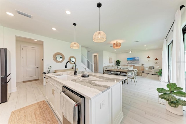 12816 Morning Mist Pl, Venice, FL 34293 - kitchen featuring stainless steel appliances, a sink, white cabinetry, light stone counters, and a kitchen island with sink