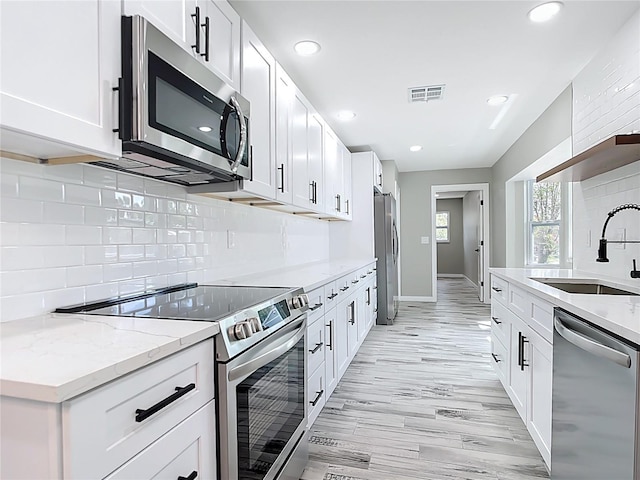7140 Teaberry St, Englewood, FL 34224 - kitchen with stainless steel appliances, a sink, backsplash, white cabinets, and recessed lighting