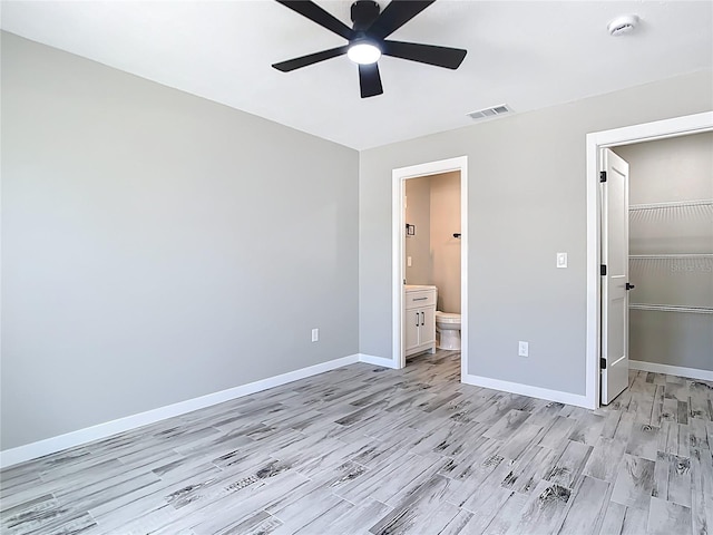 7140 Teaberry St, Englewood, FL 34224 - unfurnished bedroom with light wood-style flooring, baseboards, a closet, a walk in closet, and a ceiling fan