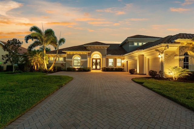 186 Portofino Dr, Nokomis, FL 34275 - mediterranean / spanish home featuring french doors, decorative driveway, a garage, a lawn, and stucco siding