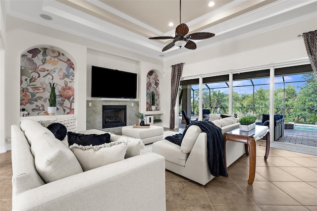 186 Portofino Dr, Nokomis, FL 34275 - living room featuring a tray ceiling, a ceiling fan, ornamental molding, plenty of natural light, and a fireplace