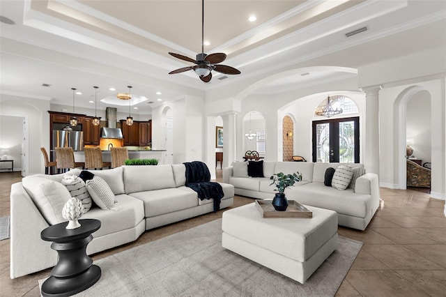 186 Portofino Dr, Nokomis, FL 34275 - tiled living room with a tray ceiling, arched walkways, ceiling fan, crown molding, and ornate columns