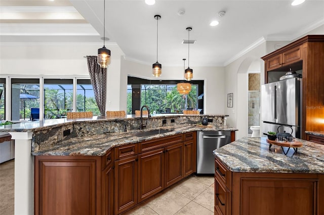 186 Portofino Dr, Nokomis, FL 34275 - kitchen with appliances with stainless steel finishes, a sink, a spacious island, arched walkways, and ornamental molding