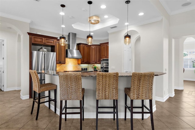 186 Portofino Dr, Nokomis, FL 34275 - kitchen featuring arched walkways, wall chimney exhaust hood, tile patterned floors, tasteful backsplash, and a kitchen breakfast bar