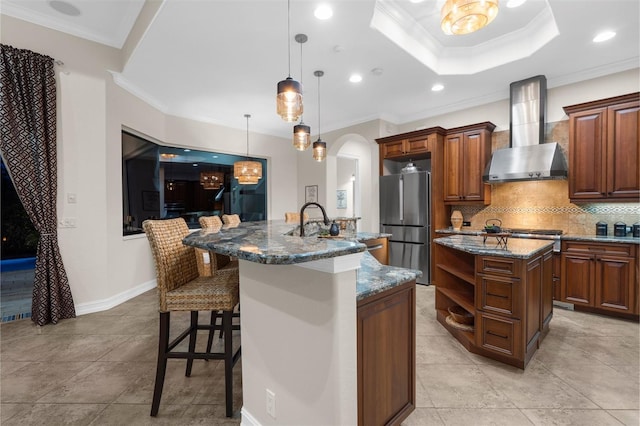 186 Portofino Dr, Nokomis, FL 34275 - kitchen featuring wall chimney exhaust hood, an island with sink, freestanding refrigerator, a kitchen breakfast bar, and ornamental molding