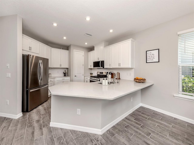 15364 Isla Palma Ln, Nokomis, FL 34275 - kitchen with stainless steel appliances, a peninsula, wood tiled floors, a sink, and recessed lighting