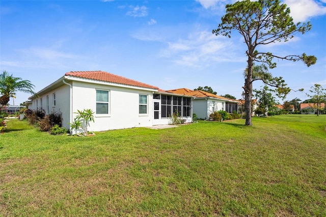 4378 Summertree Rd, Venice, FL 34293 - rear view of house featuring a yard, stucco siding, a sunroom, and a tile roof